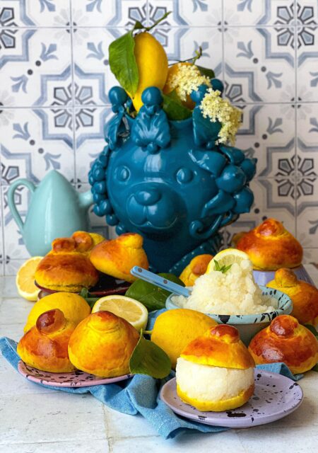 Piatto con brioche farcita con la granita, poi dietro le brioche e sullo sfondo una testa di orso ceramica artigianale di Caltagirone