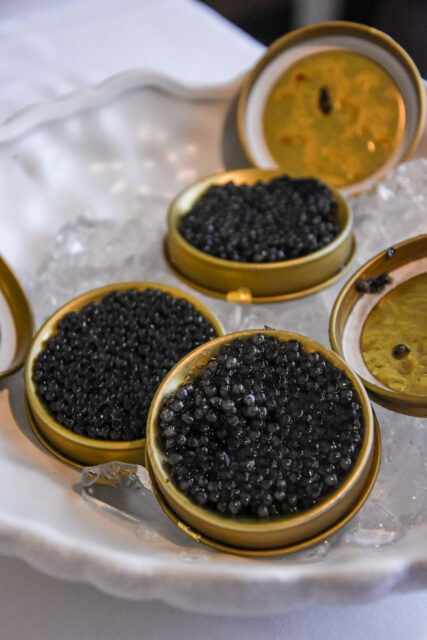 Tre vasetti di caviale aperti e poggiati su un piatto pieno di ghiaccio