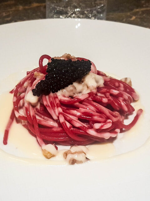 Piatto di spaghetti rosa con crema di parmigiano e sopra caviale