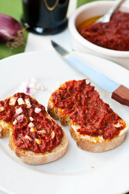 Due crostini con sopra la sardella spalmata. Su uno anche della cipolla rossa tritata.