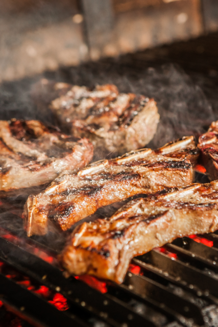 Griglia con carboni ardenti sotto e sopra carne che cuoce
