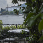 Una terrazza vista lago con piante e tavolo e sedie in ferro battuto