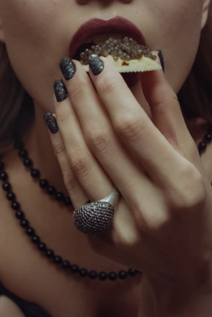 Una donna mette in bocca un crostino con il caviale