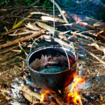 Un pentolone messo su un fuoco fatto con la legna in mezzo alla natura