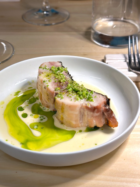 Un trancio di aguglia imperiale nel piatto con un olio verde e una salsa chiara