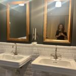 Bagno con 2 lavelli e una persona riflessa nello specchio