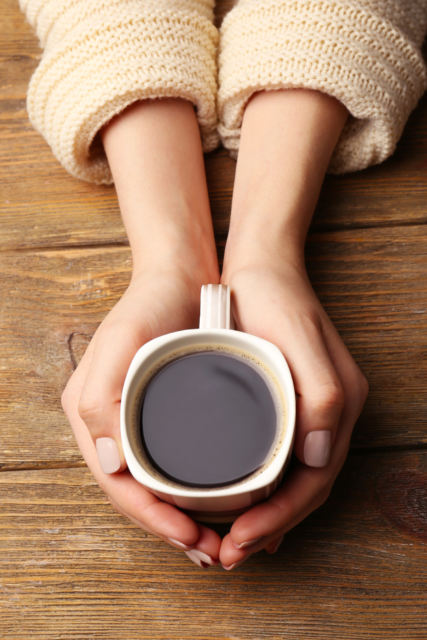 due mani stringono una tazza con caffè dentro