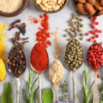 Rametti di erbe aromatiche, cucchiaini pieni di spezie e ciotole con frutta secca